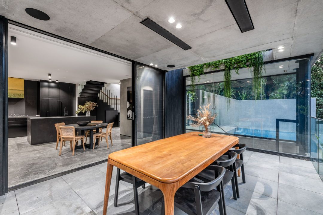 Open-plan dining area with a timber table and concrete floor in a Merewether home