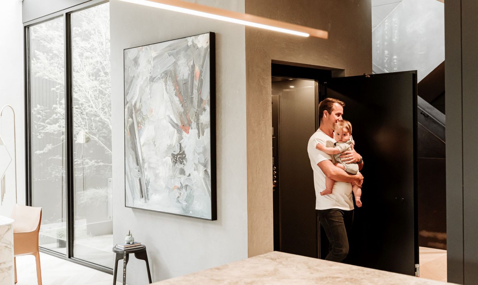 Father carrying his baby out of the open E1 swing door lift beside the stairs in an inner Melbourne home