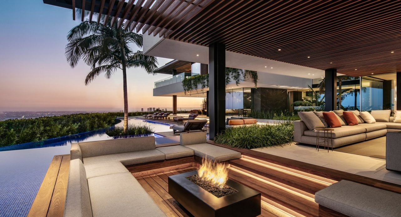 Sunken fire pit lounge on the terrace at sunset with palm trees and city views over Los Angeles
