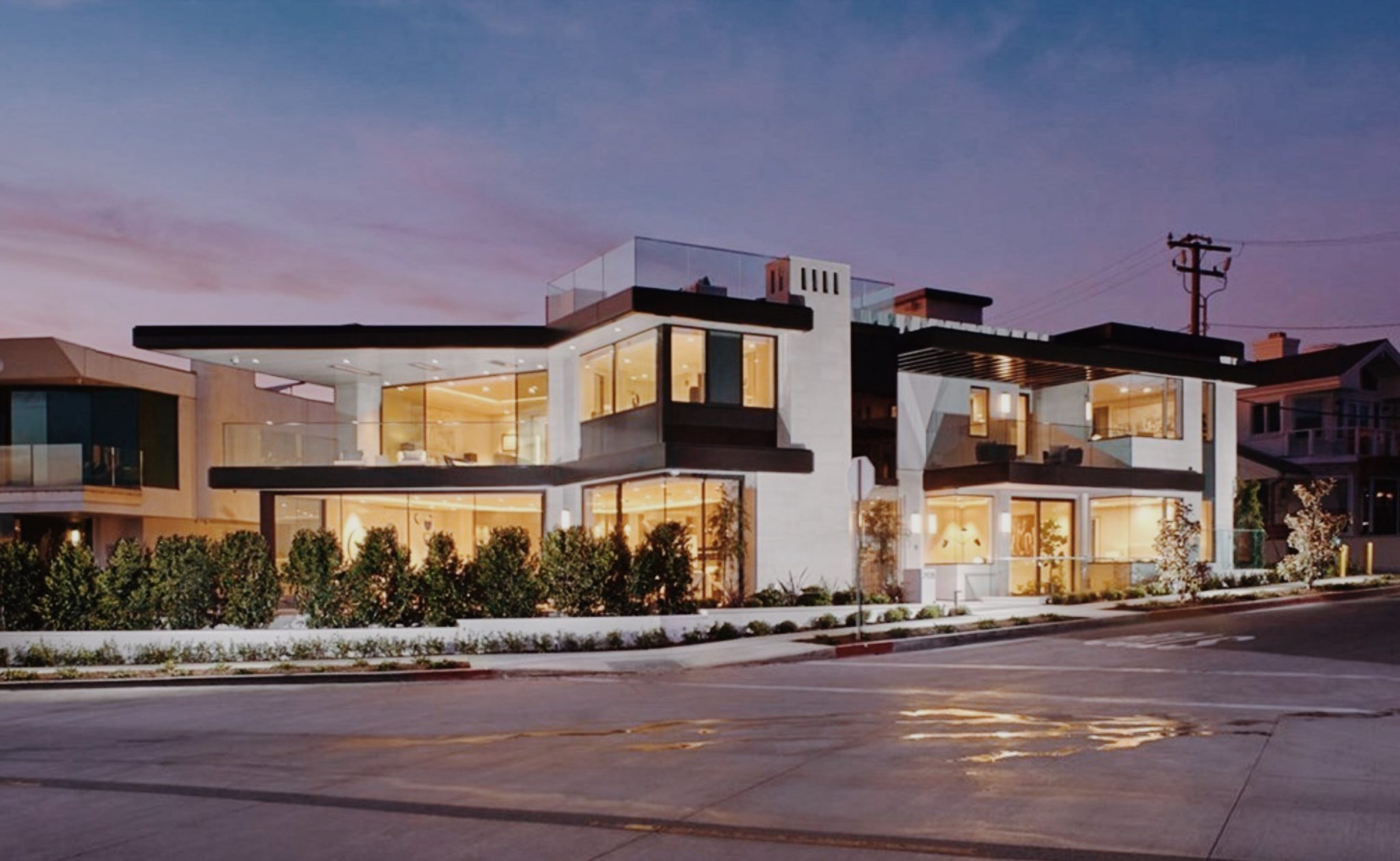 Modern glass-fronted mansion in Corona Del Mar, Newport Beach, lit up at dusk, home to a six-stop electric lift