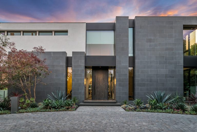 Dark stone clad modern house at dusk with a timber front door in Beverly Hills