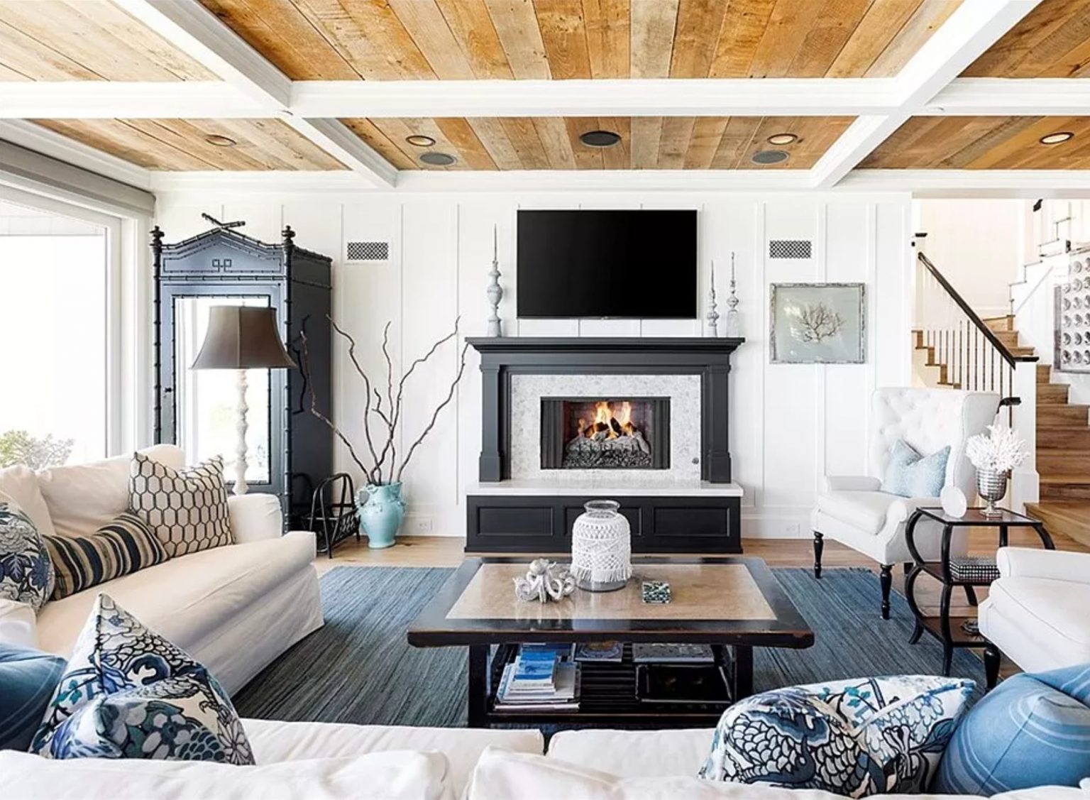 Coastal living room with a timber and white coffered ceiling, fireplace and blue and white furnishings