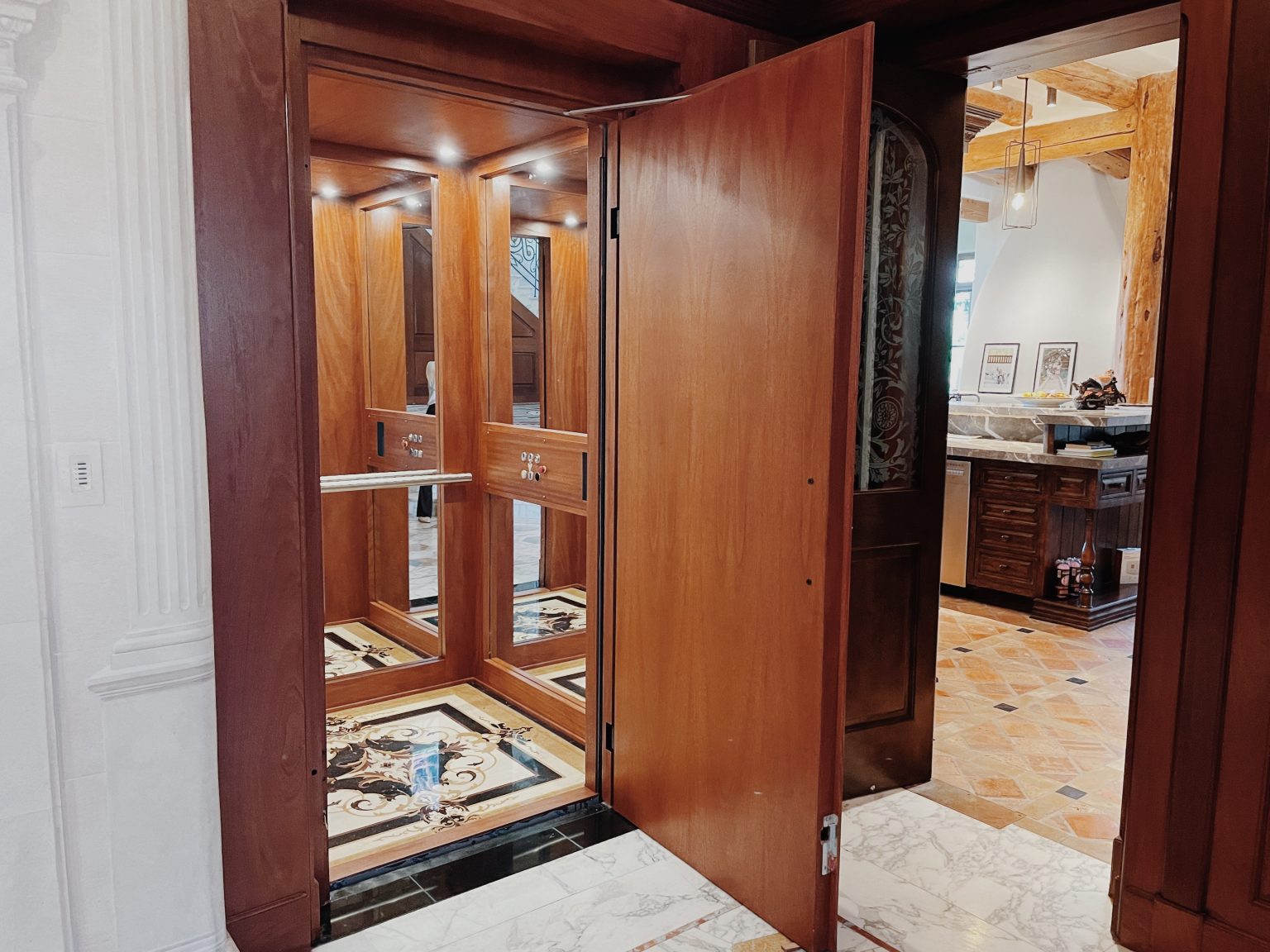 Classica cabin lift with the timber door open, raised wall trims and a warm wood interior in the Malibu home