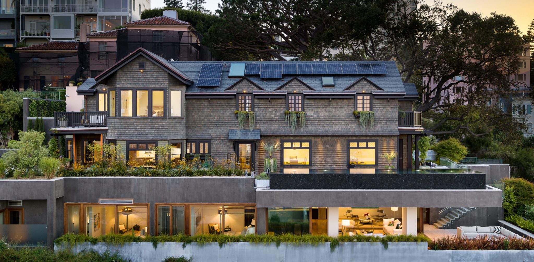 Shingle-clad Lombard Street estate in San Francisco at dusk, with solar panels on the roof and terraced gardens