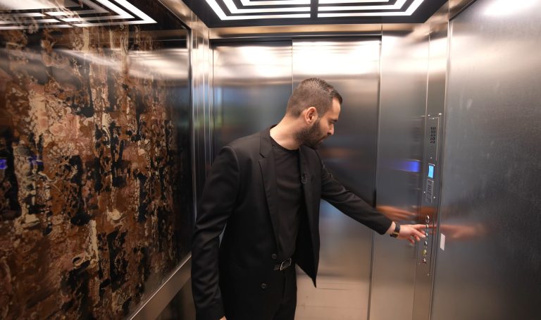 Man pressing a button on the stainless control panel with display and keypad inside the lift cabin