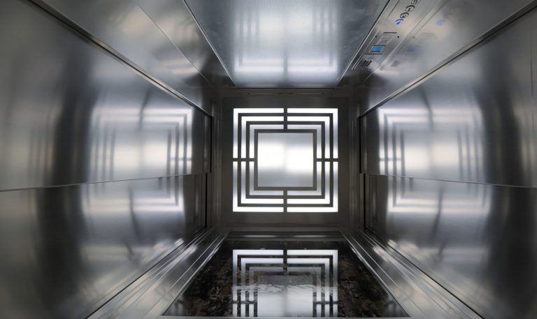 Looking up the stainless steel lift cabin at the square art deco ceiling light