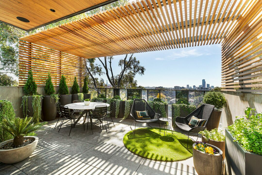 Timber slatted pergola over a terrace with outdoor furniture, planters and a city view in Melbourne