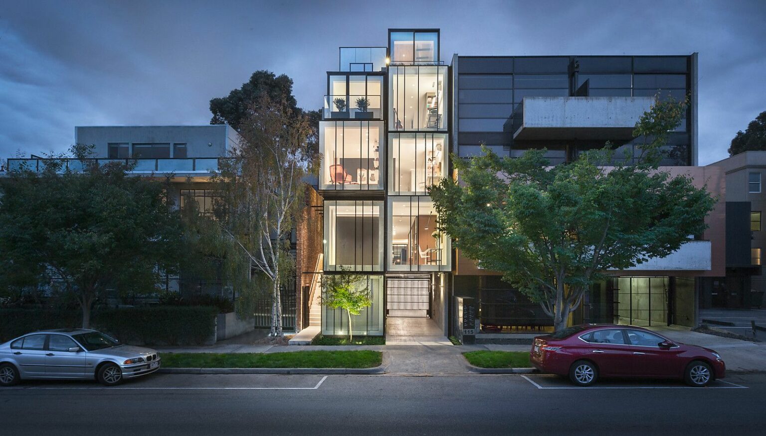 Multi-level glass and steel building at dusk on a Melbourne street with trees out the front