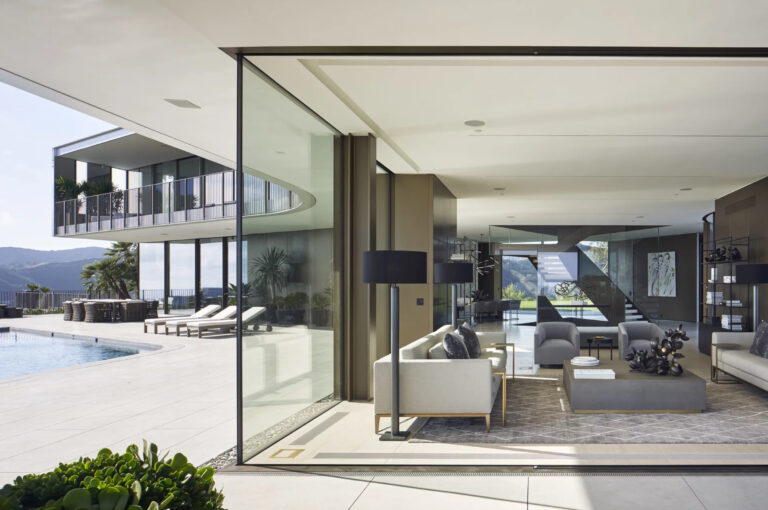 Living room opening through a glass wall to a pool terrace and hills in Bel Air