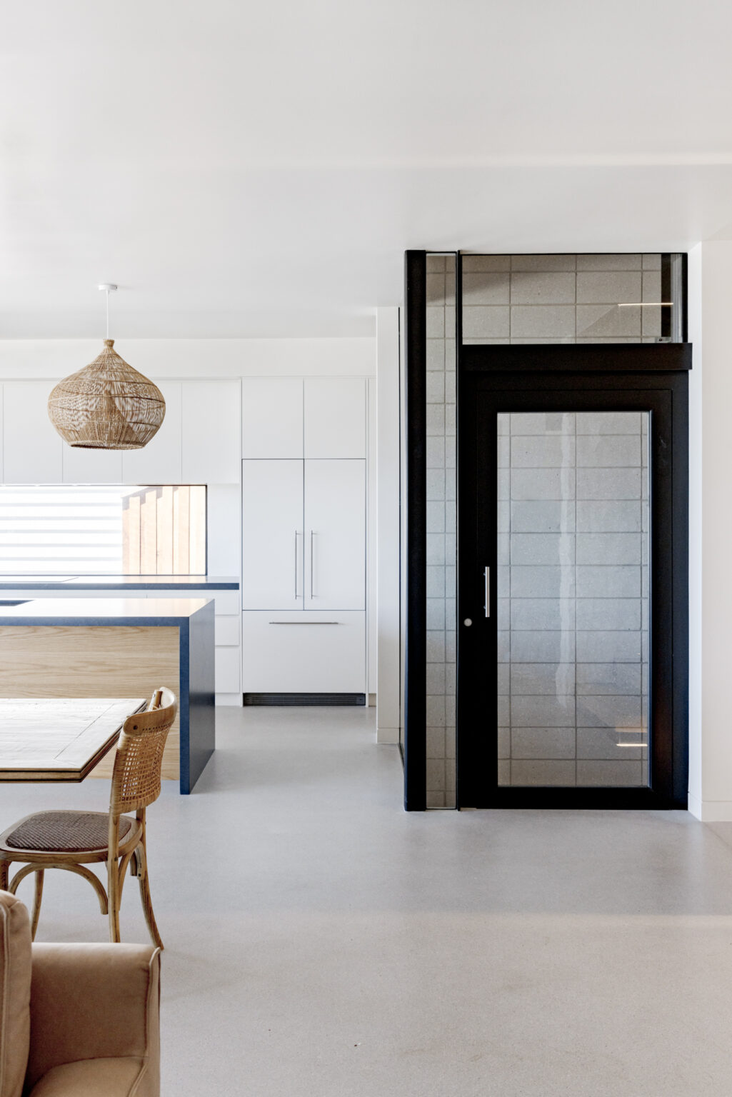 Glass A Series lift tiled to match the limestone, with a black door frame, beside the open-plan kitchen at Avoca Beach