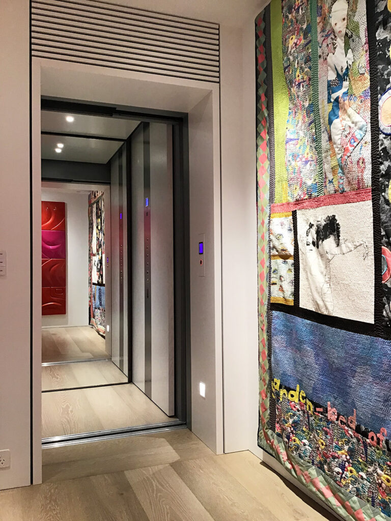 E2 lift opening onto a hallway with colourful artwork and a timber floor