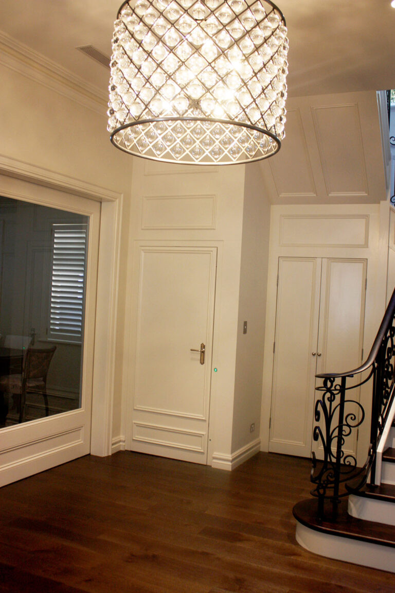 Crystal chandelier above the hallway with panelled doors and a timber floor