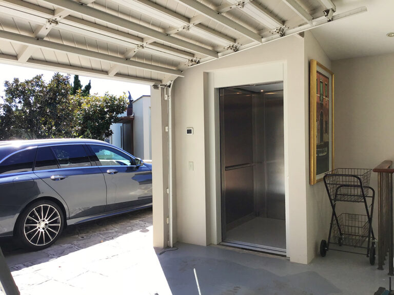 Home lift with stainless doors beside a garage with a car parked in Mosman