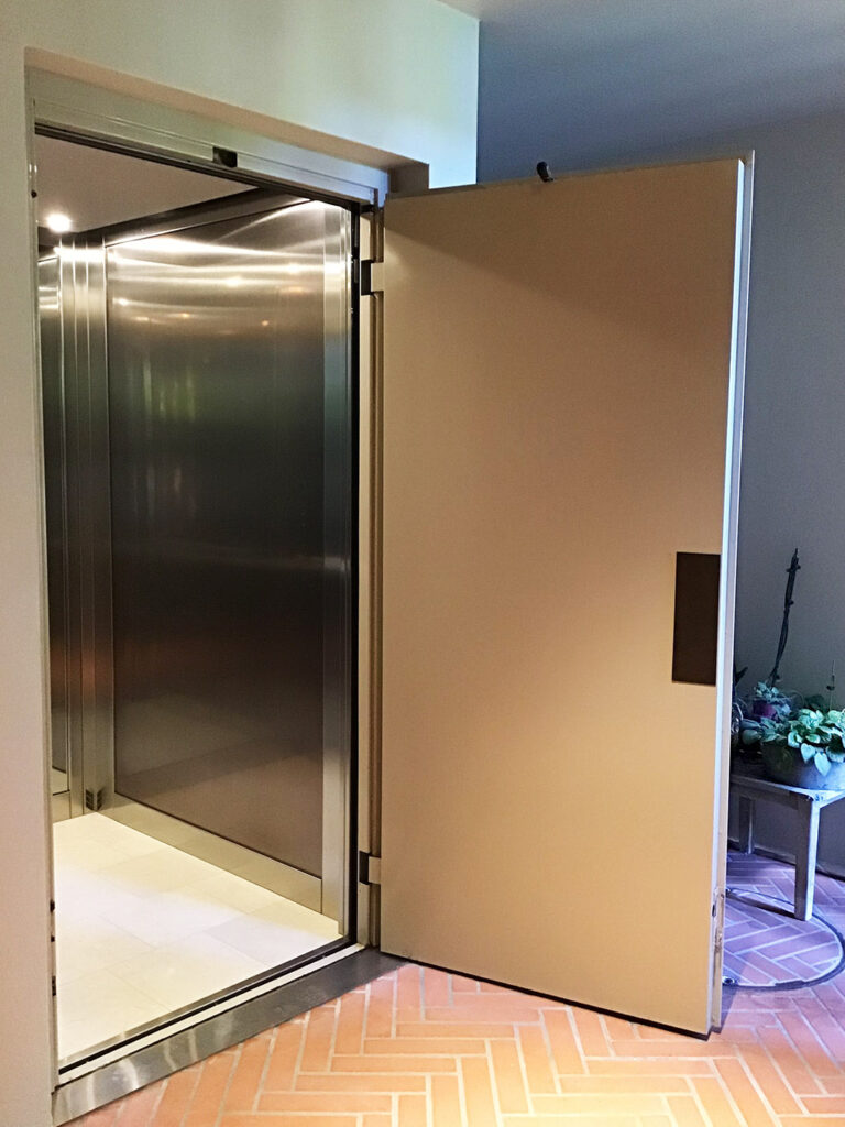 Open timber-faced door beside a stainless steel lift car in a Mosman home