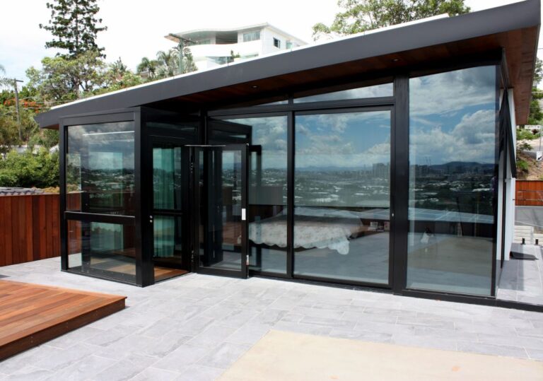 Black framed glass lift enclosure with a skillion roof on a paved terrace in Balmoral