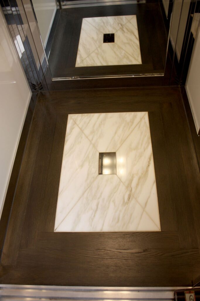 Looking down at the marble inlay set in the dark timber floor of the duplex lift