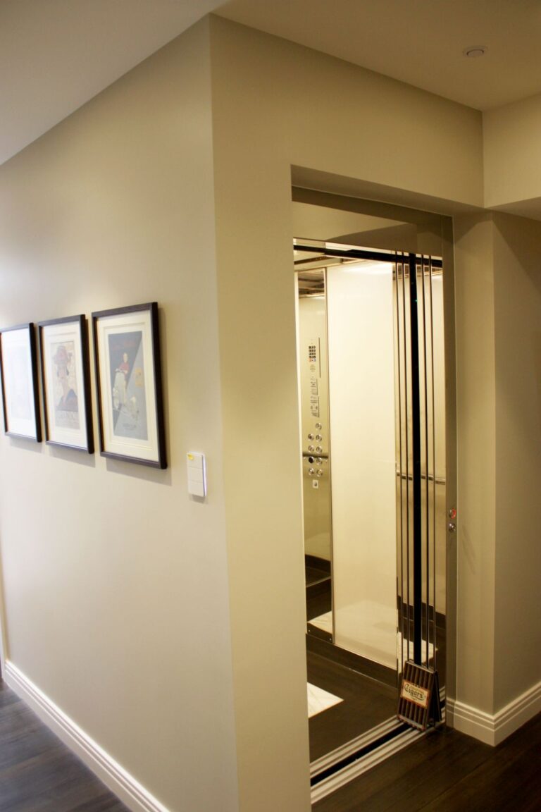 Hallway with framed pictures leading to the open E2 lift door in the duplex