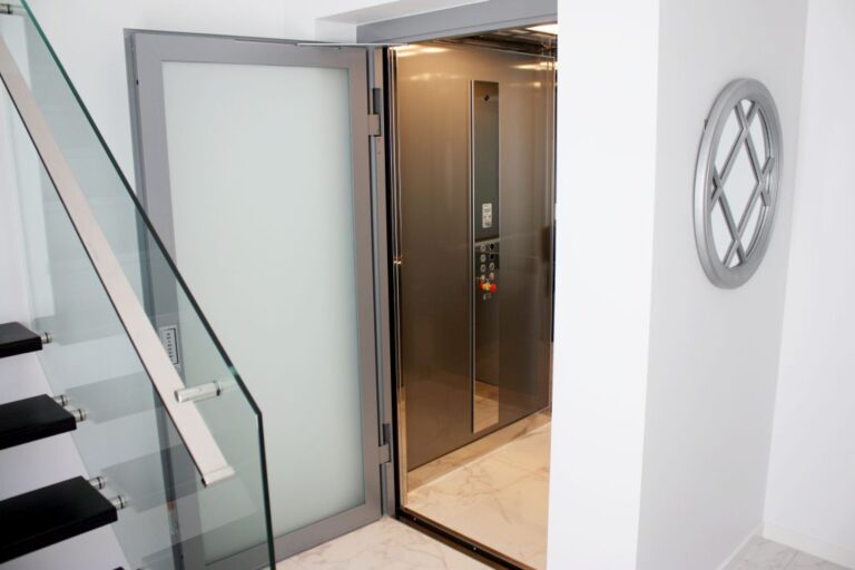 Lift door with a frosted glass panel beside a glass stair balustrade