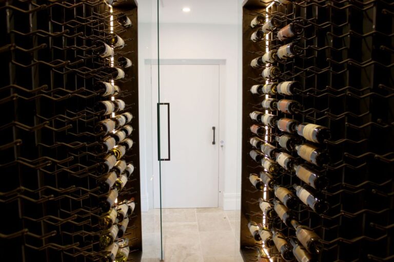 Wine racks either side of a glass door leading to a white door