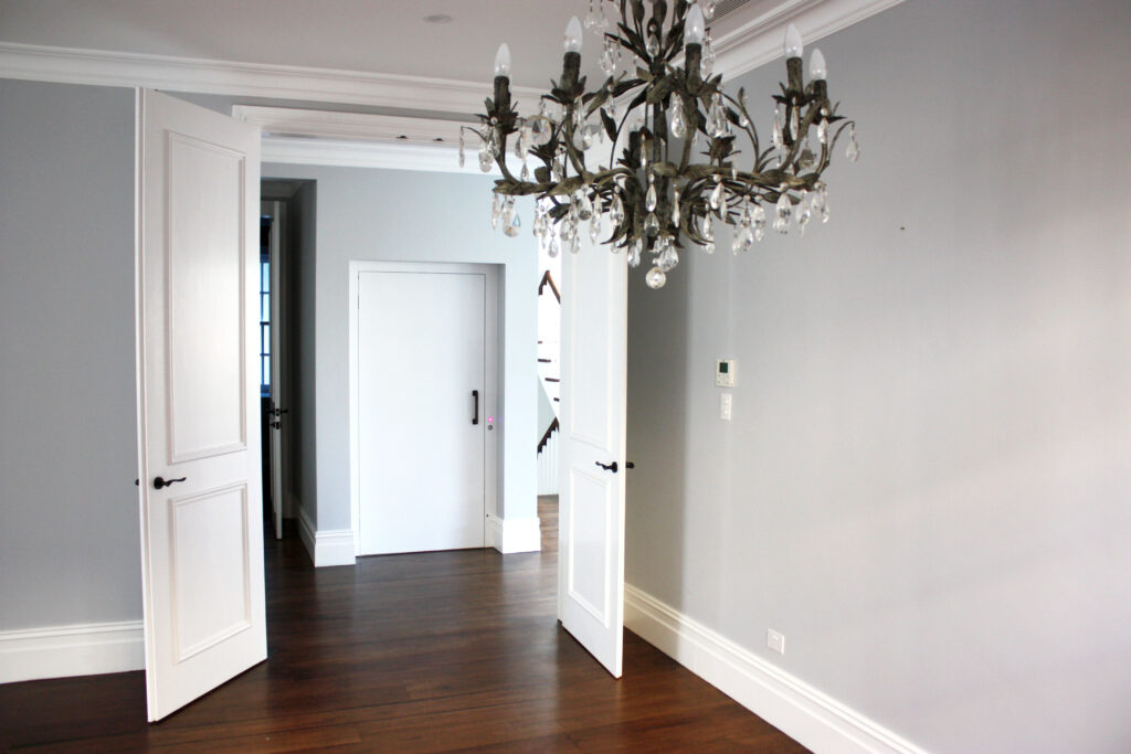 Room with a chandelier and open white double doors onto a hallway in the Rose Bay home