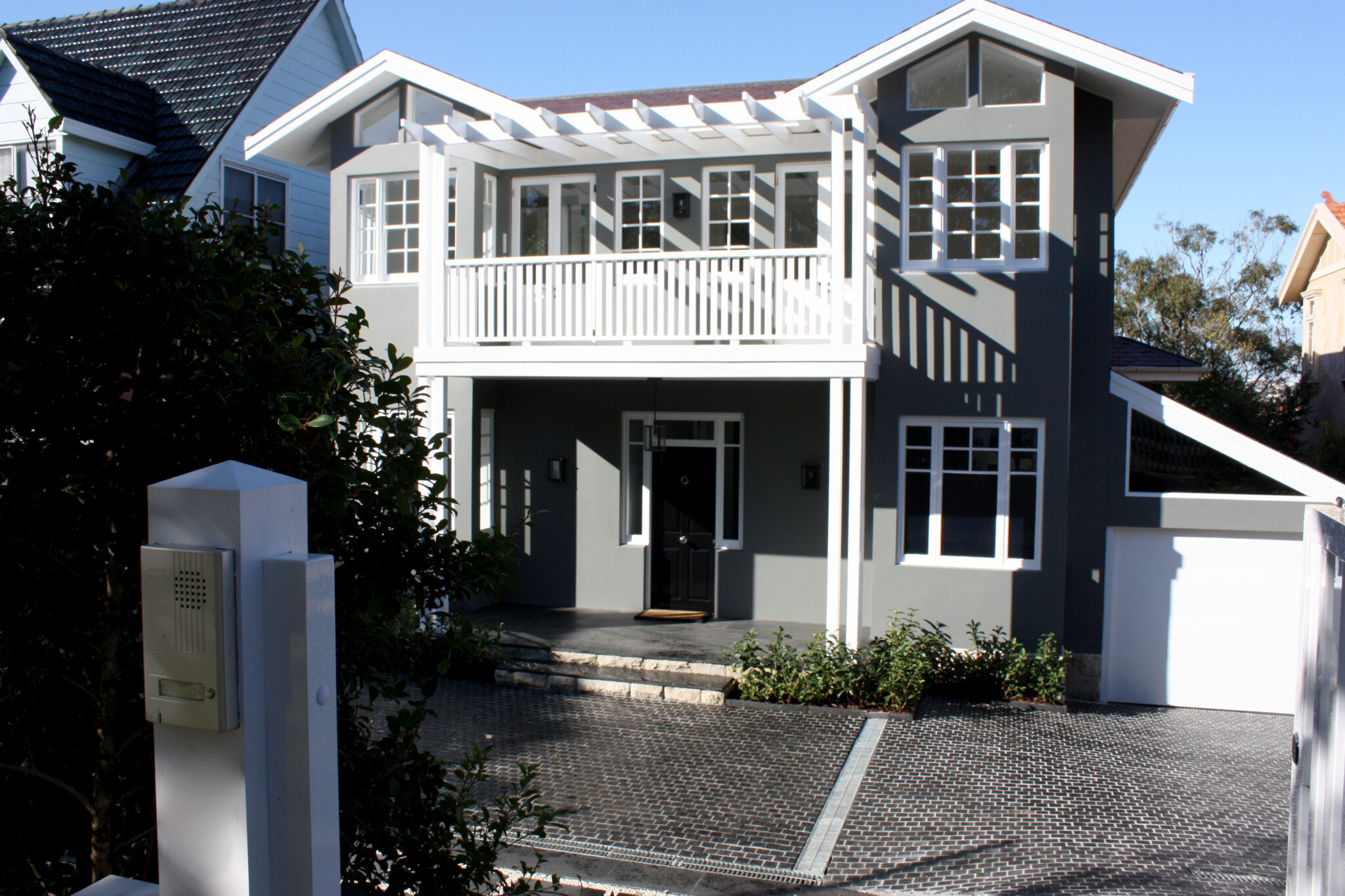 Two storey grey and white house in Rose Bay with a balcony, paved driveway and entry