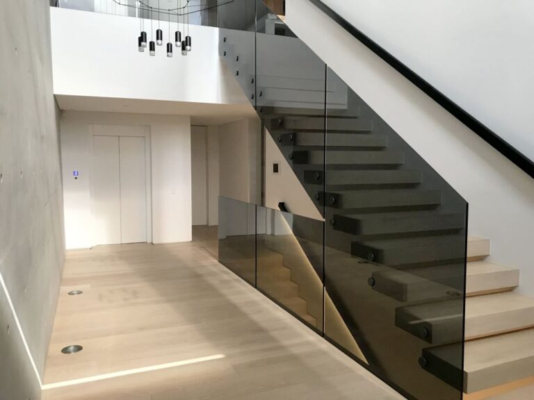 Concrete walled entry hall with a floating staircase and lift door in a Maroubra home