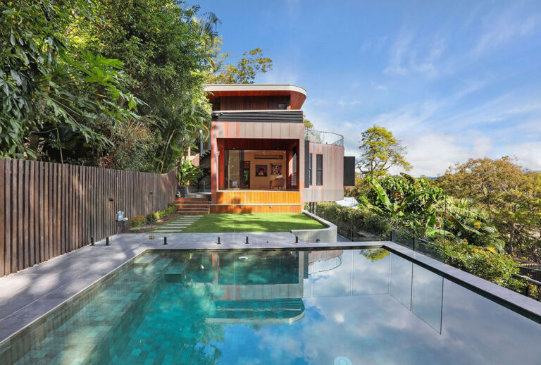 Contemporary timber clad home above a lawn and a glass edged pool on a Currumbin hillside
