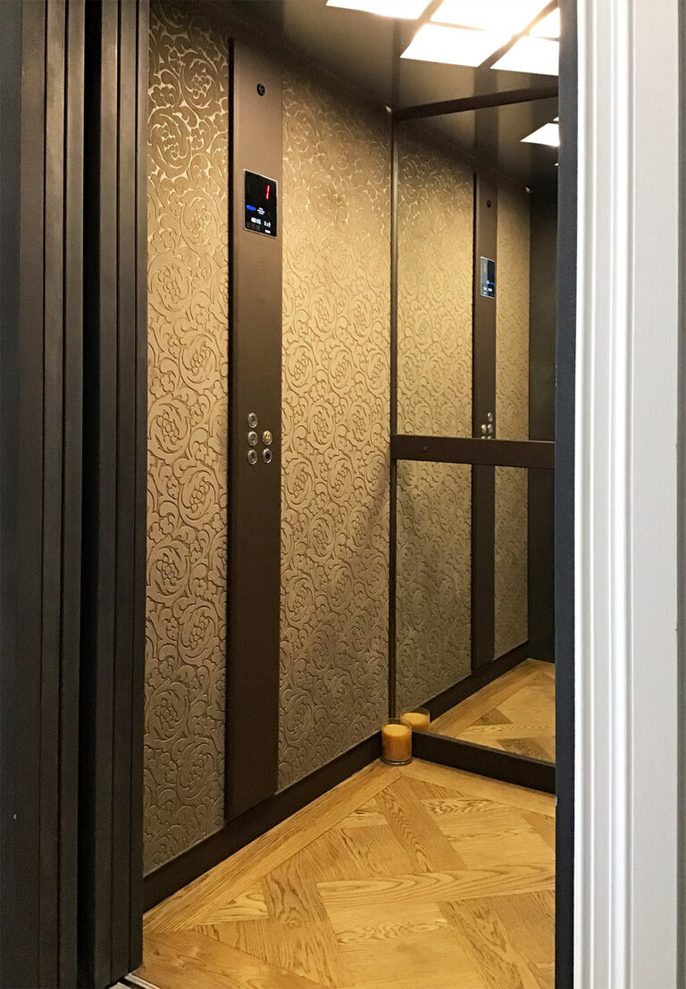 Inside the lift car with velvet feature walls, a control panel, a mirror and a parquetry floor