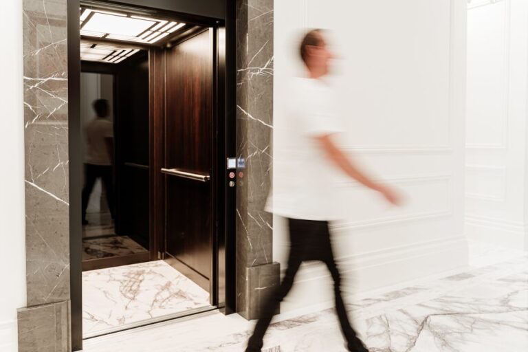 A person walking past the open lift with its marble surround and dark timber interior, Leura Grove