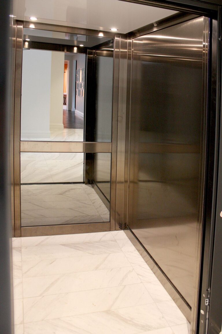 Inside the Distinction lift cabin with bronze metal walls and a marble look floor