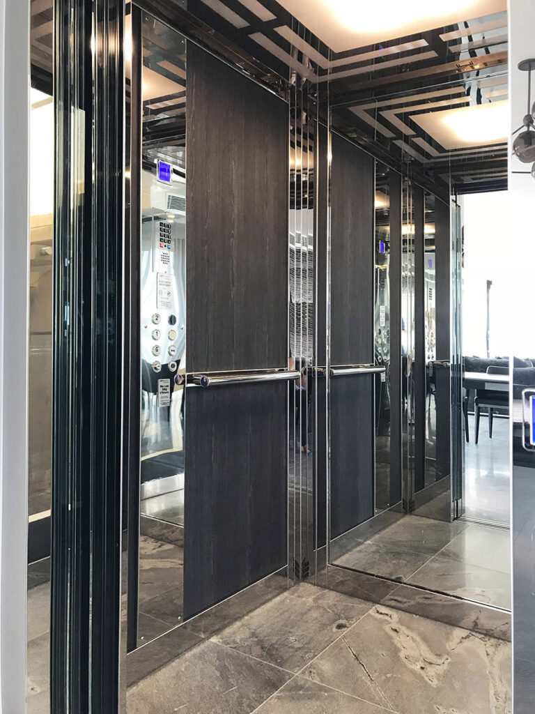 Inside the two-stop E2 home lift in Dover Heights: dark timber wall panels, mirror, polished stainless steel trim and a stone floor