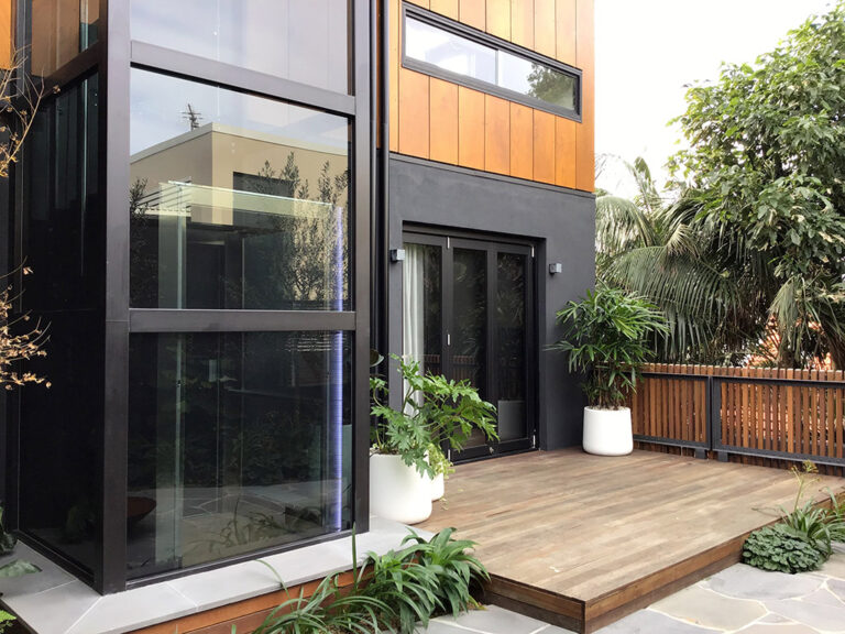 The glass shaft beside the timber deck and a sliding door in the Coogee garden