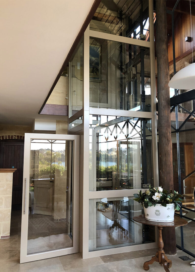 Glass lift with a pale metal frame beside timber posts in North Fremantle