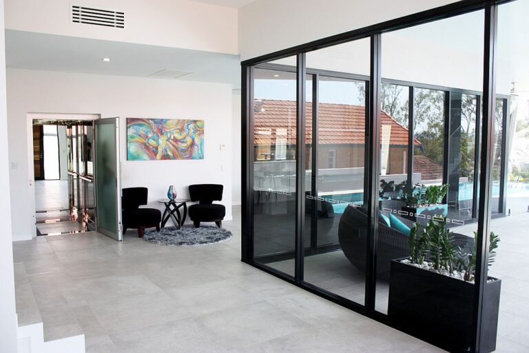 Living area with large black framed sliding glass doors beside the lift door