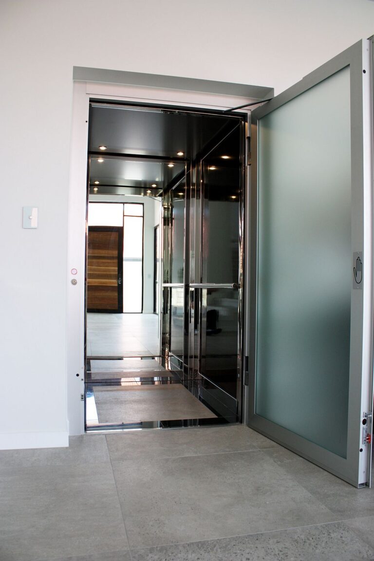 Open E1 lift door with a frosted glass panel on a grey tiled floor, near Brisbane