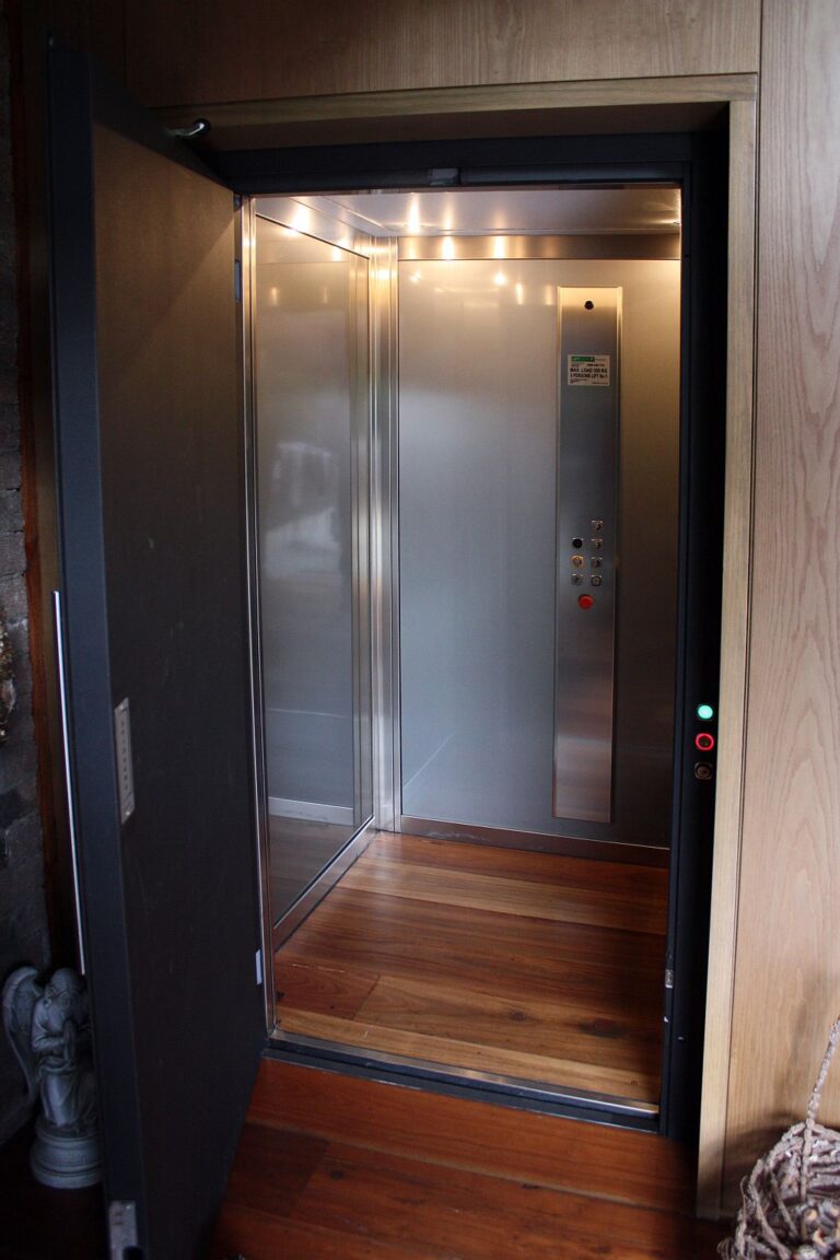 Inside a lift car with stainless steel panelling and a timber floor