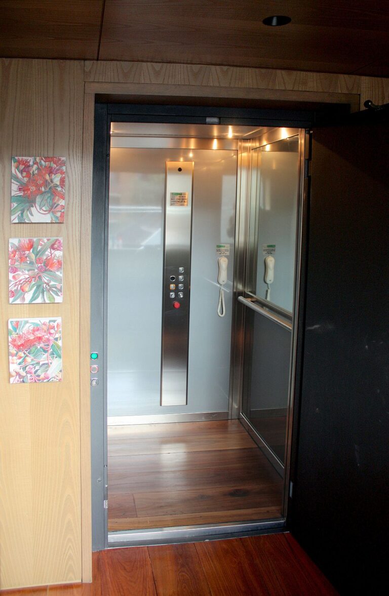 Lift car with a stainless steel panel and timber floor seen through a black framed door