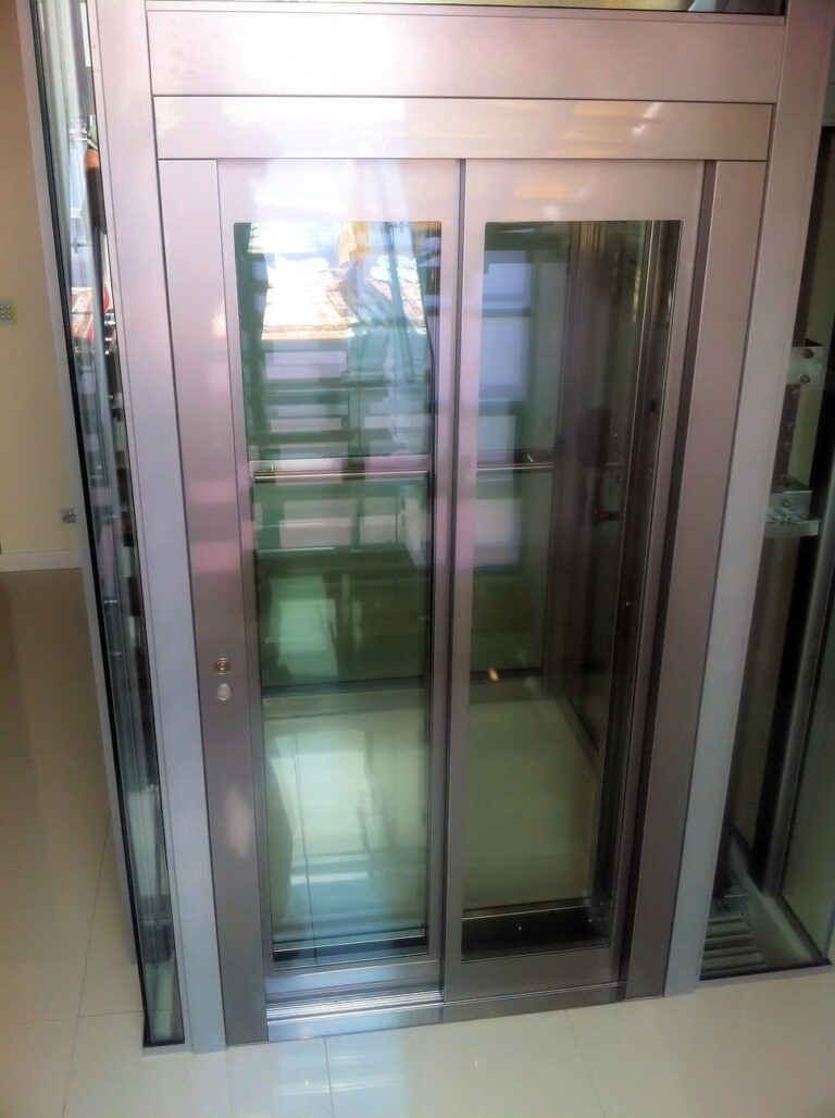 Panoramic glass landing doors of the Elfo 2 in brushed stainless steel frames
