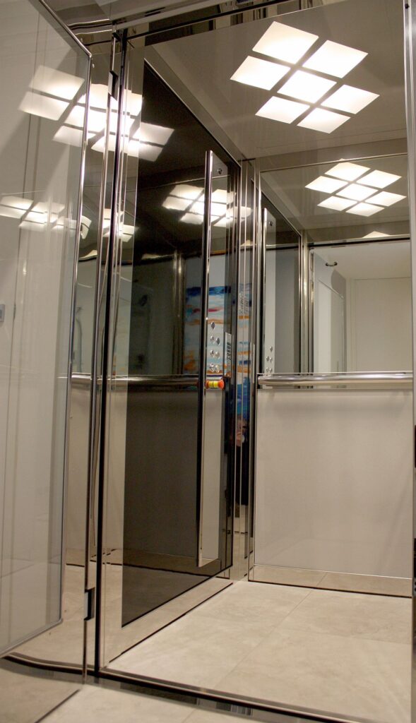 Inside the mirrored E1 lift cabin with a polished stainless steel frame, black laminate wall and ceiling light panels