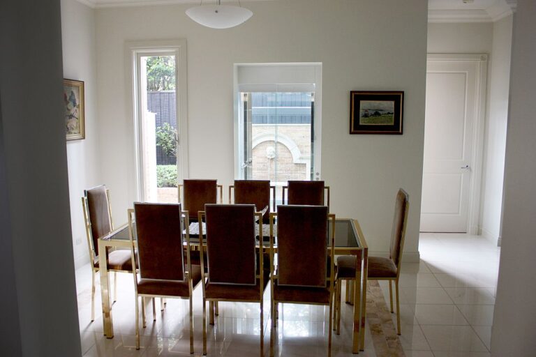 Dining room with a glass-topped table and brown chairs beside the window that looks onto the Toorak courtyard