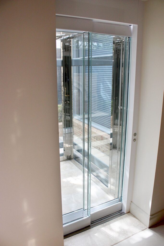Frameless sliding glass lift door opening onto the Toorak courtyard