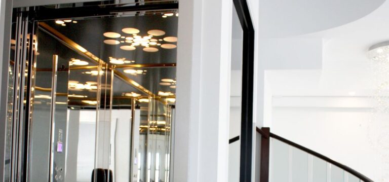 Lift car with a mirrored ceiling and circular lights beside a stair balustrade in Wellington Point