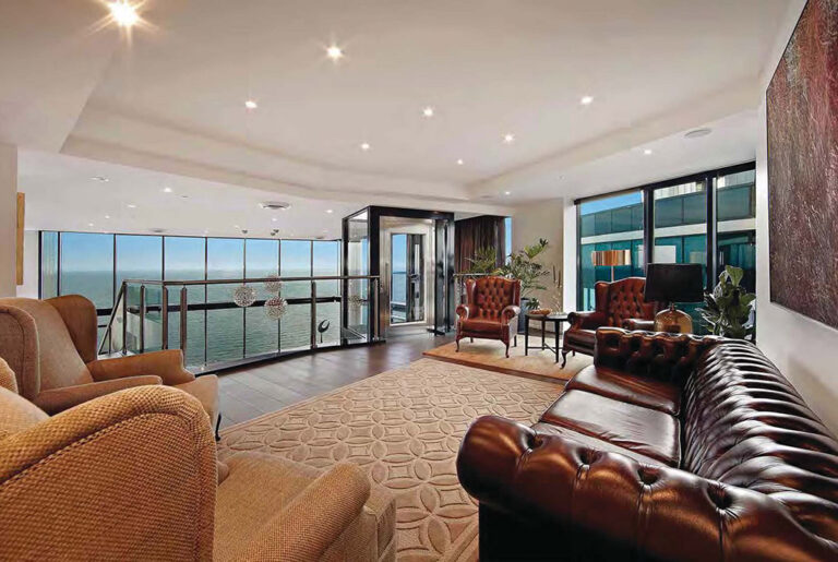 Penthouse living room with leather sofas and ocean views through floor to ceiling windows in Melbourne