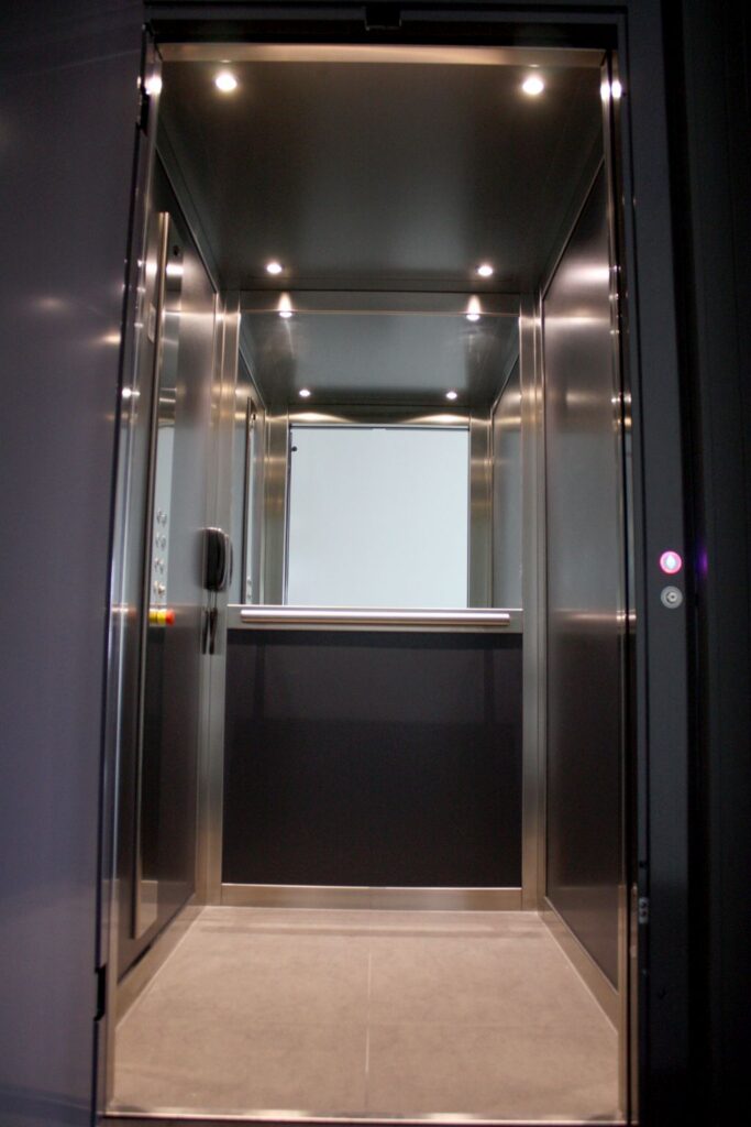 Elfo E1 lift in the charcoal Coorparoo home with a mirrored back wall, stainless steel trim and ceiling downlights