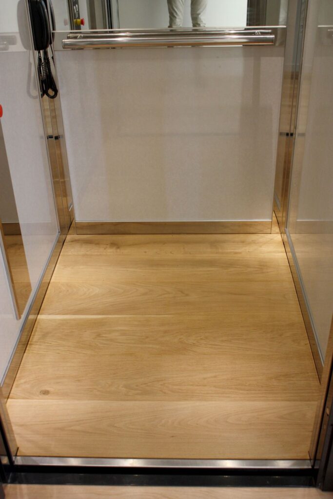 Timber floor of the lift cabin with a stainless steel threshold and a mirror above