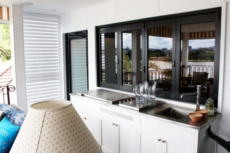 Enclosed balcony with a white kitchenette and black framed windows with a river view in Newmarket