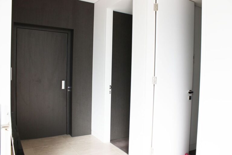 Dark timber veneer lift door set into a matching feature wall beside white doors in a Bellevue Hill hallway