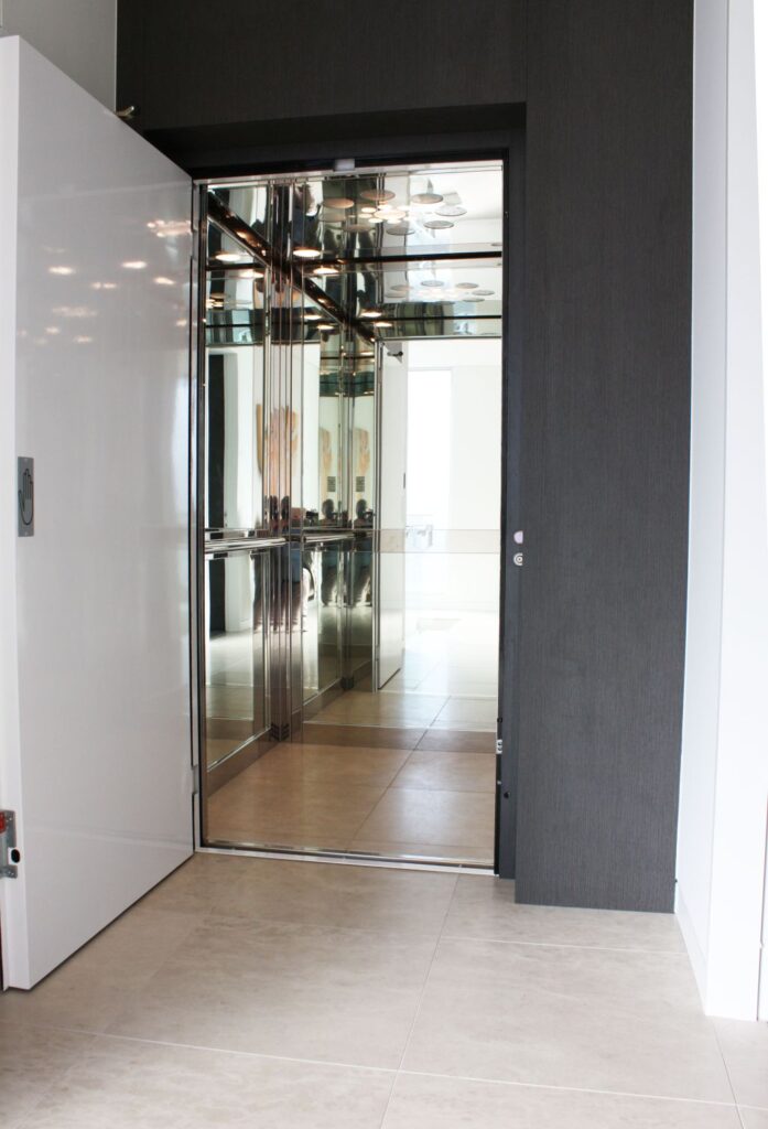 The E1 lift car with its door open, showing mirrored walls, stainless steel profiles and a mirrored ceiling