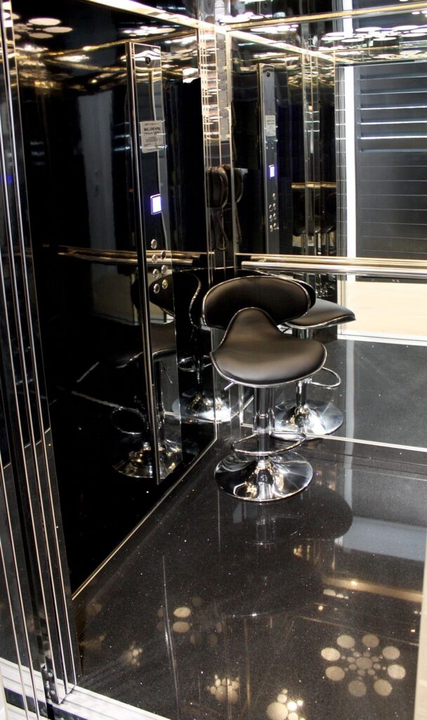 Black leather bar stool on a chrome base inside the mirrored black and stainless ElfoLift 2 cabin