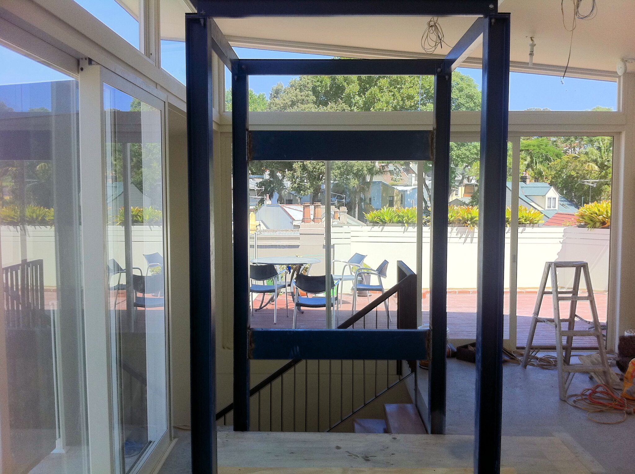 Steel lift shaft frame going in beside the stairwell of an existing home, at the start of the retrofit